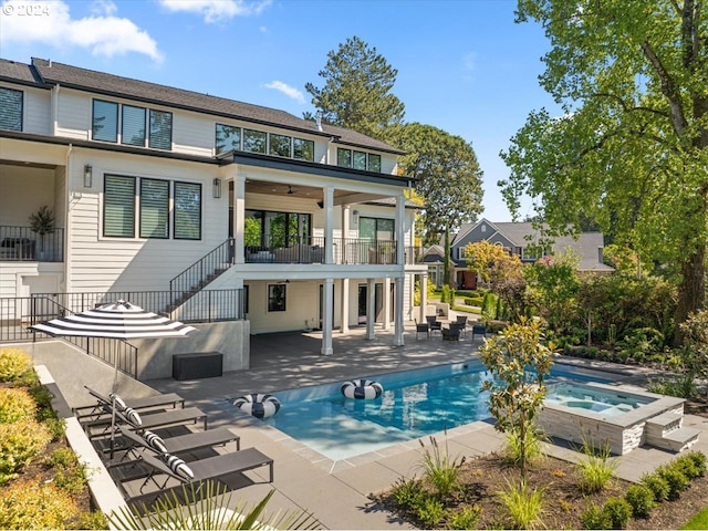 rear view of property featuring ceiling fan, a swimming pool with hot tub, and a patio area