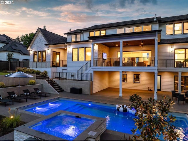 pool at dusk featuring an in ground hot tub and a patio area