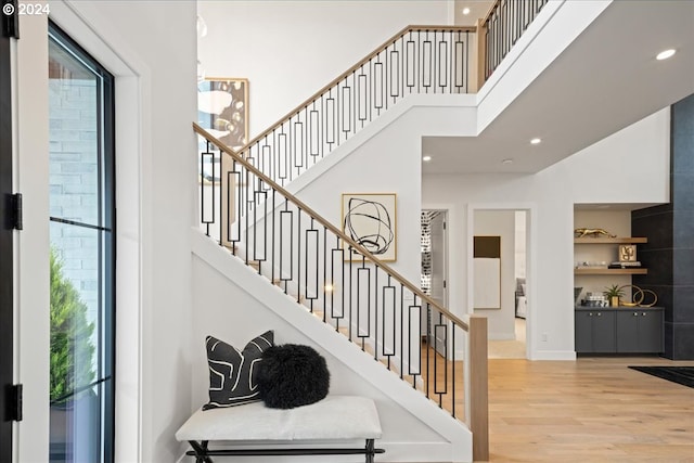 staircase with a towering ceiling, hardwood / wood-style floors, and a wealth of natural light