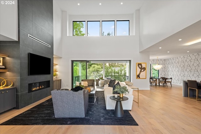 living room featuring a high ceiling, a tiled fireplace, and plenty of natural light