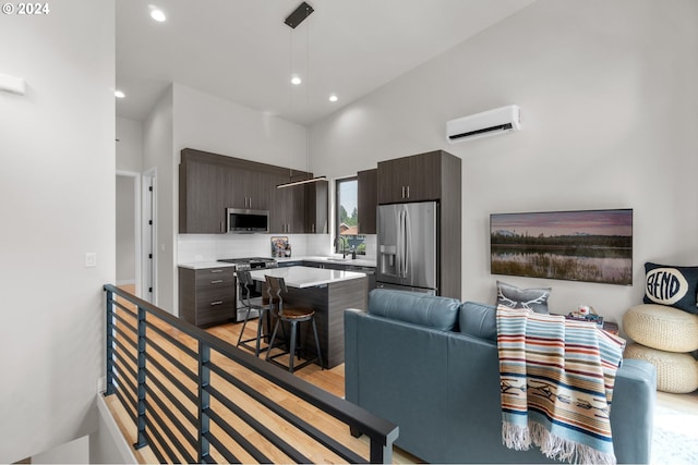 living room featuring light hardwood / wood-style floors, sink, an AC wall unit, and a towering ceiling