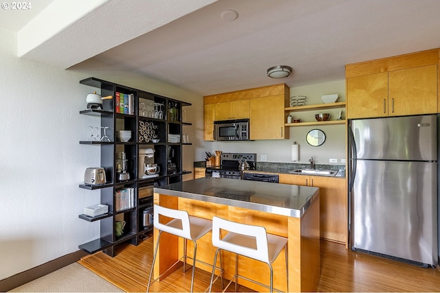 kitchen featuring a kitchen island, stainless steel counters, stainless steel appliances, hardwood / wood-style flooring, and sink