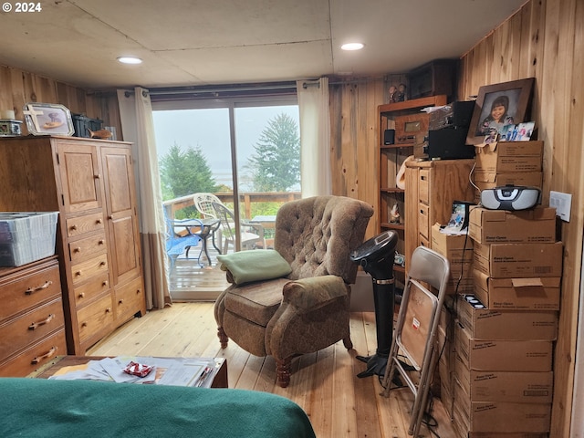 bedroom with wooden walls, a wall mounted air conditioner, and light hardwood / wood-style flooring