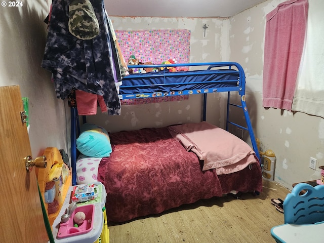 bedroom with light hardwood / wood-style floors, wood walls, and access to exterior