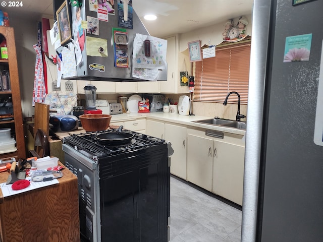 kitchen with gas stove, white cabinets, stainless steel fridge, and sink