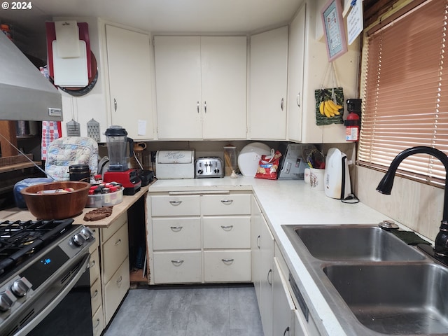 kitchen featuring sink, wood-type flooring, black gas range oven, white cabinetry, and range hood