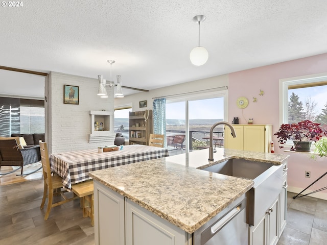 kitchen featuring white cabinets, a textured ceiling, hanging light fixtures, and an island with sink