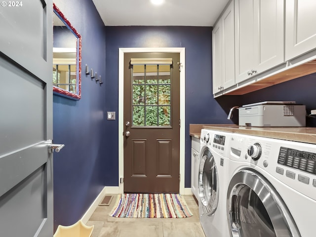 laundry area with washer and clothes dryer, cabinets, and light tile patterned floors