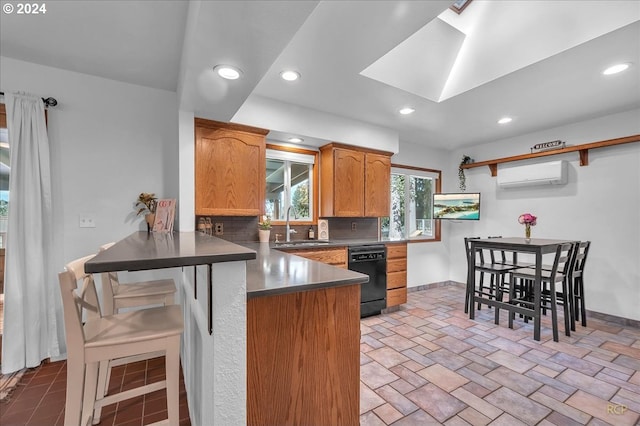 kitchen with a wall unit AC, decorative backsplash, kitchen peninsula, black dishwasher, and a skylight