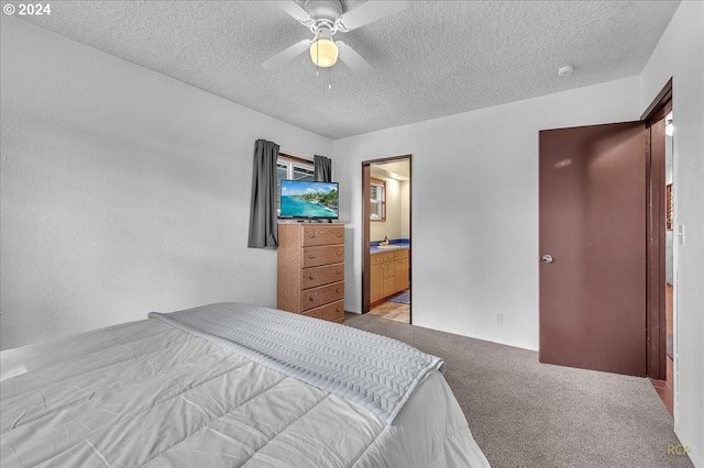 bedroom with ceiling fan, connected bathroom, a textured ceiling, and light carpet