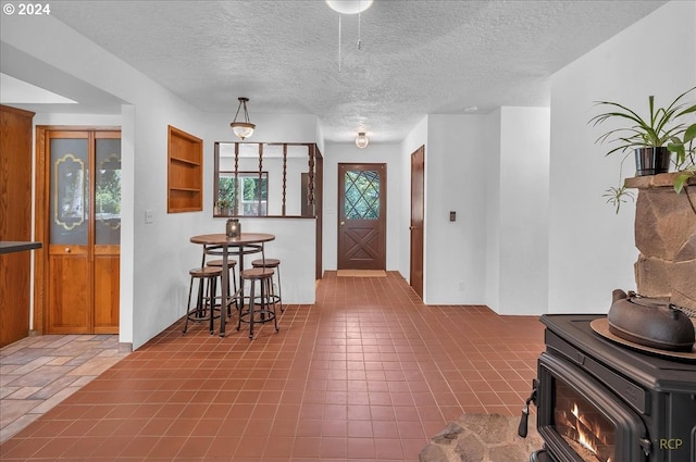 foyer entrance featuring a textured ceiling and a wood stove