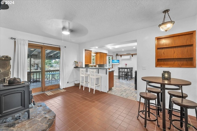 dining area featuring dark tile patterned flooring, ceiling fan, a textured ceiling, and a wood stove