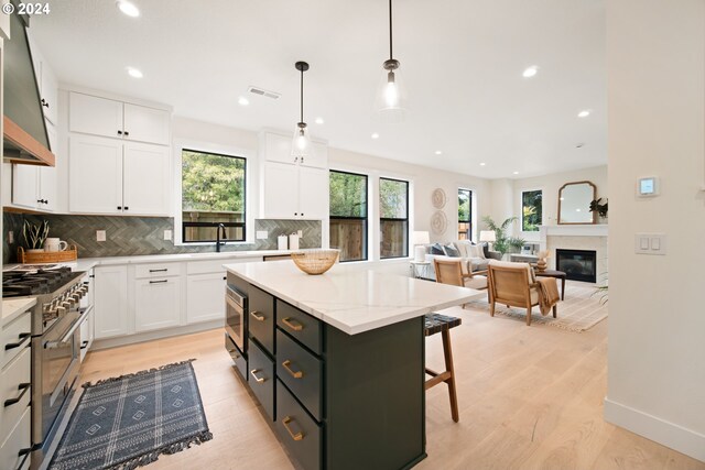 kitchen featuring hanging light fixtures, white cabinetry, high end stove, and a kitchen island