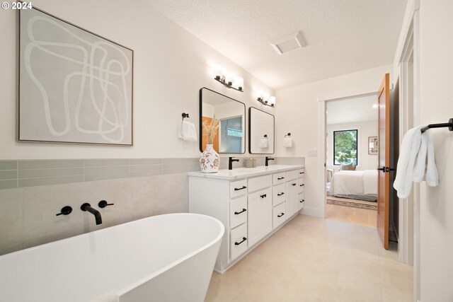 bathroom with a textured ceiling, a washtub, tile patterned floors, and vanity