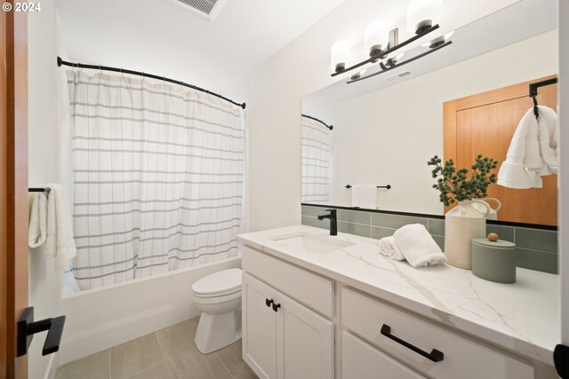 full bathroom featuring toilet, vanity, tile patterned floors, and shower / tub combo with curtain