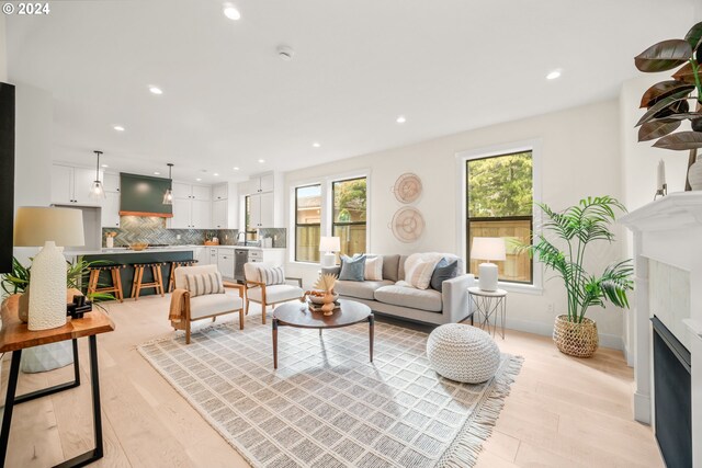 living room with a high end fireplace, light wood-type flooring, and a healthy amount of sunlight