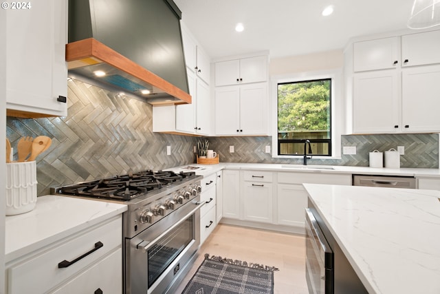 kitchen with high end range, white cabinetry, and custom range hood