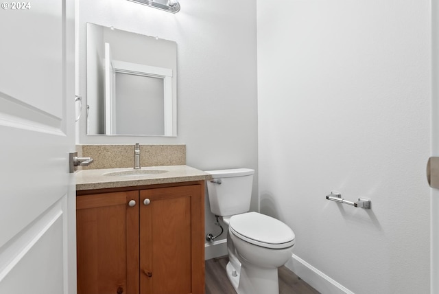 bathroom with toilet, vanity, and hardwood / wood-style flooring