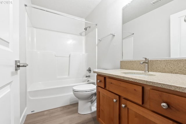 full bathroom with vanity, a textured ceiling, shower / washtub combination, wood-type flooring, and toilet