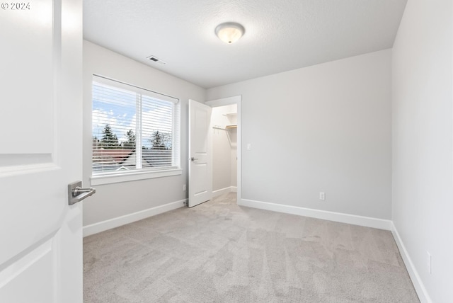 empty room featuring a textured ceiling and light colored carpet