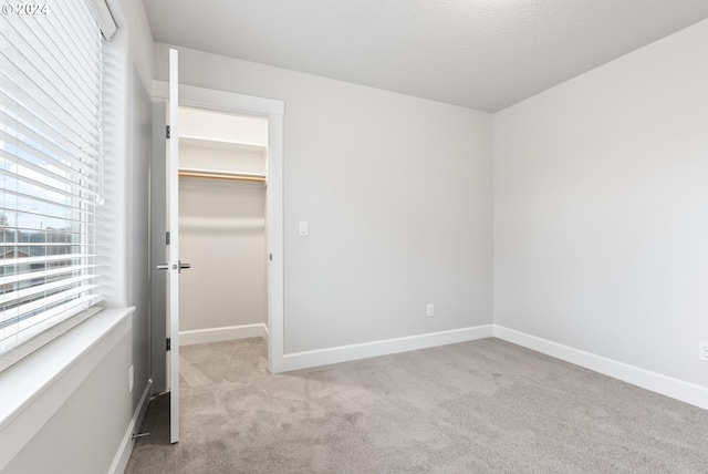 unfurnished bedroom featuring light colored carpet, a spacious closet, and a closet