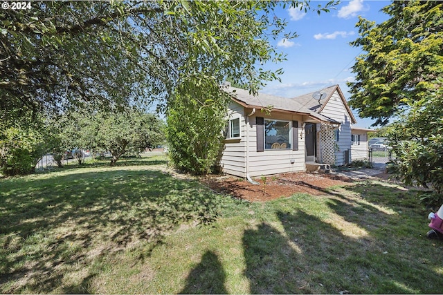 view of side of home featuring a lawn and fence