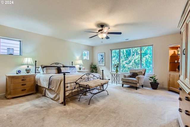 bedroom featuring ceiling fan, light carpet, and multiple windows