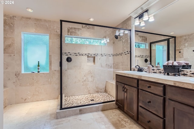 bathroom featuring vanity, tiled shower, tile walls, and a wealth of natural light