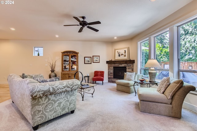 carpeted living room featuring a fireplace and ceiling fan