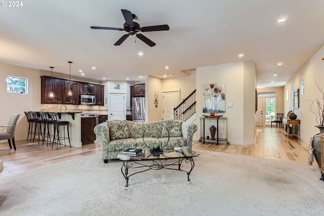 living room featuring ceiling fan and light hardwood / wood-style flooring