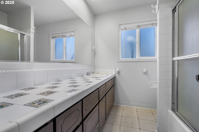 full bath with a sink, baseboards, and double vanity