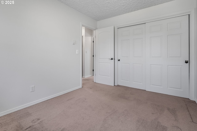 unfurnished bedroom with carpet flooring, baseboards, a closet, and a textured ceiling