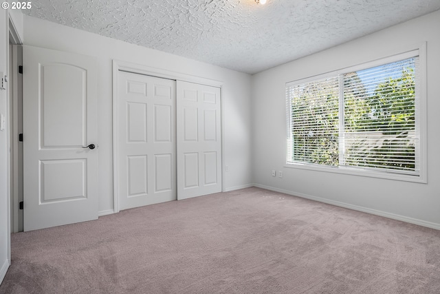 unfurnished bedroom featuring a closet, baseboards, a textured ceiling, and carpet flooring