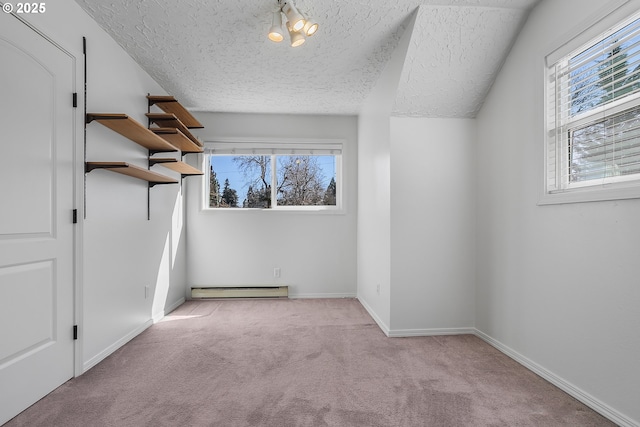 additional living space with a baseboard radiator, carpet floors, a textured ceiling, and baseboards