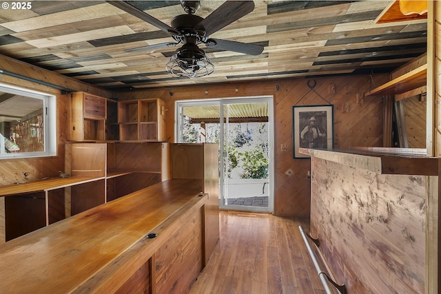 doorway featuring wooden walls, ceiling fan, and wood finished floors