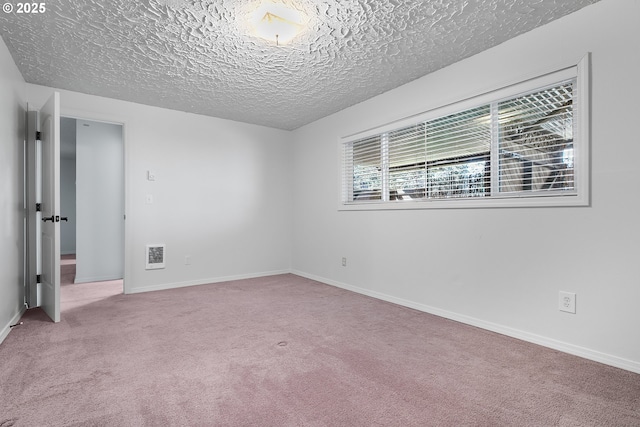 carpeted spare room featuring visible vents, baseboards, and a textured ceiling