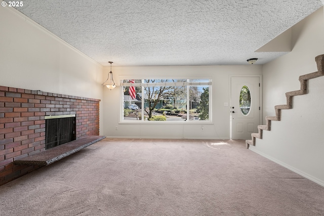 unfurnished living room with stairway, carpet flooring, a brick fireplace, and a textured ceiling