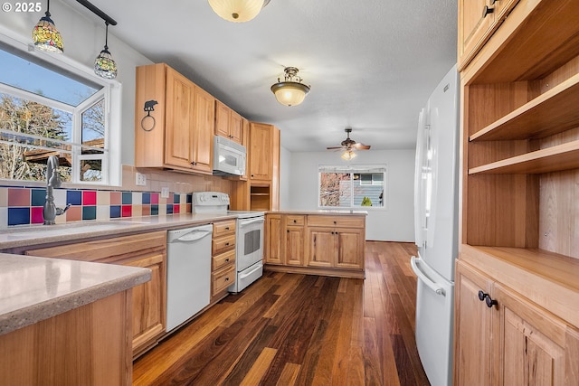 kitchen featuring a sink, white appliances, dark wood-type flooring, and a wealth of natural light