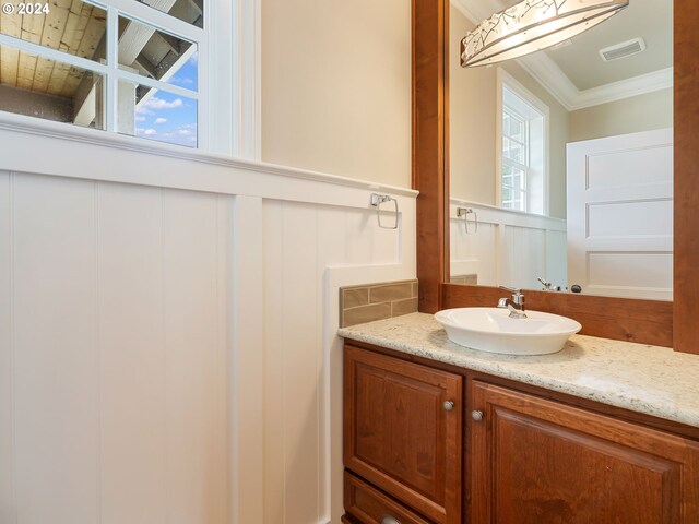 bathroom featuring a wealth of natural light, ornamental molding, and vanity