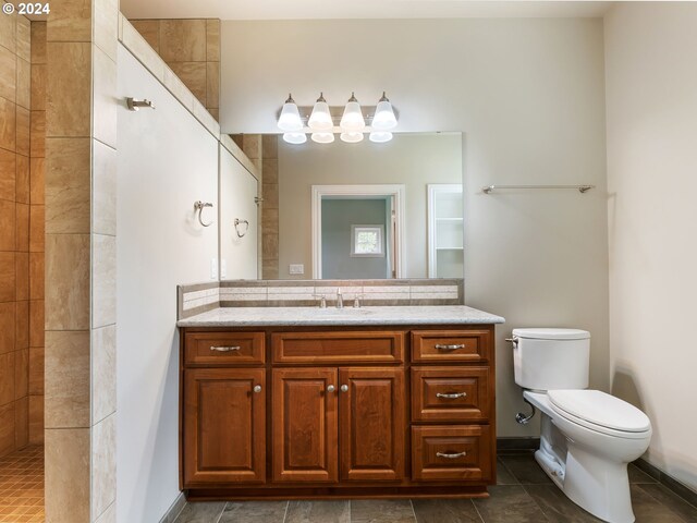 bathroom featuring tiled shower, toilet, tile patterned floors, and vanity