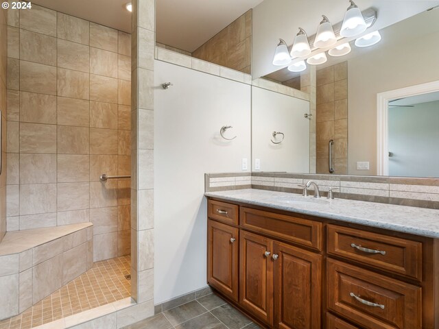 bathroom with tiled shower, tile patterned flooring, vanity, and tile walls