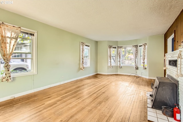 unfurnished living room featuring light hardwood / wood-style flooring, a textured ceiling, and a healthy amount of sunlight