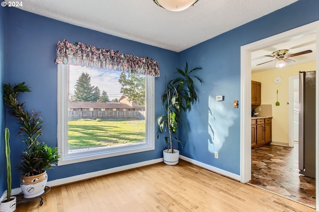 unfurnished room with ceiling fan, a textured ceiling, and light wood-type flooring