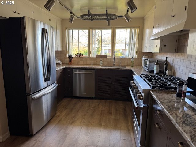 kitchen featuring hardwood / wood-style floors, white cabinetry, sink, stainless steel appliances, and light stone countertops