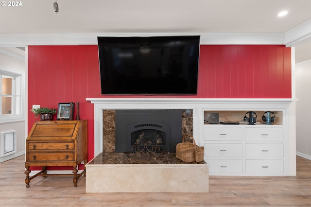 living room featuring crown molding, light hardwood / wood-style flooring, and a premium fireplace