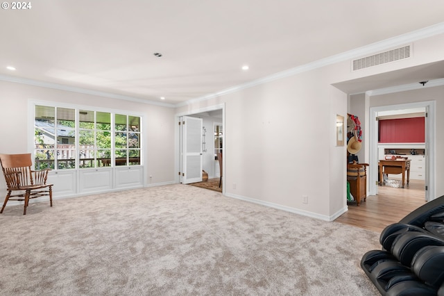 living area with crown molding and light carpet