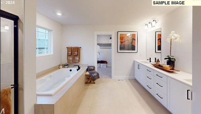 bathroom with vanity, a relaxing tiled tub, and tile patterned floors