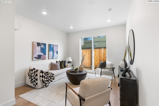 living room featuring a wall mounted air conditioner and light hardwood / wood-style flooring