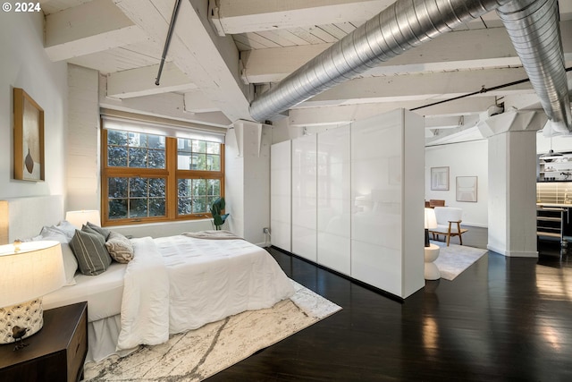 bedroom with beamed ceiling and dark hardwood / wood-style flooring