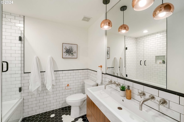 bathroom featuring vanity, toilet, walk in shower, tile walls, and tile patterned flooring